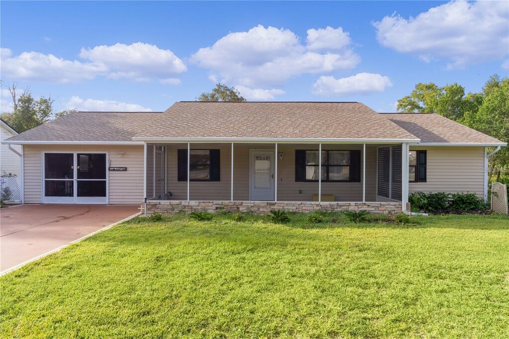 ranch-style house featuring covered porch and a front lawn