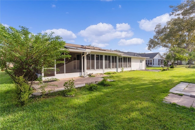 rear view of house featuring a sunroom and a yard