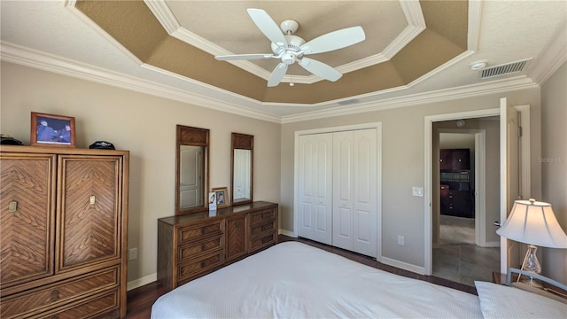 bedroom with ceiling fan, dark hardwood / wood-style floors, ornamental molding, a tray ceiling, and a closet