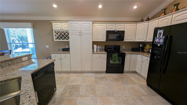 kitchen with black appliances, light stone counters, white cabinetry, and ornamental molding