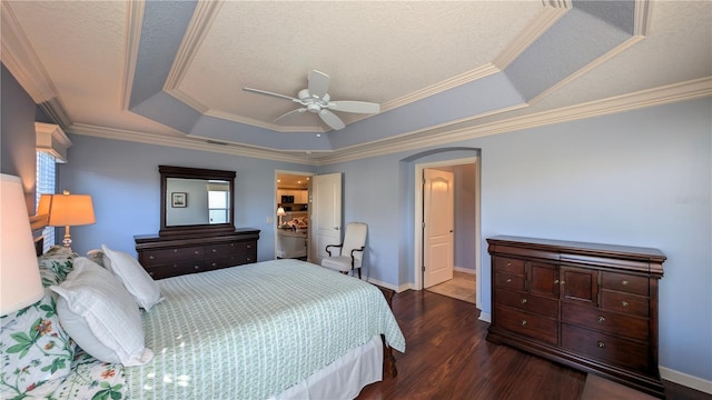 bedroom featuring ensuite bath, ceiling fan, dark hardwood / wood-style flooring, a tray ceiling, and ornamental molding