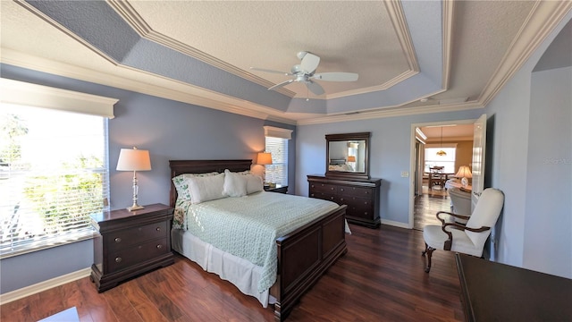 bedroom with dark hardwood / wood-style flooring, a tray ceiling, ceiling fan, crown molding, and multiple windows