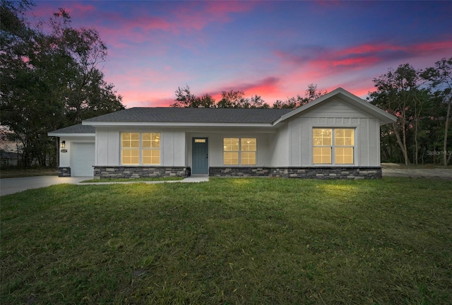 single story home featuring a garage and a yard