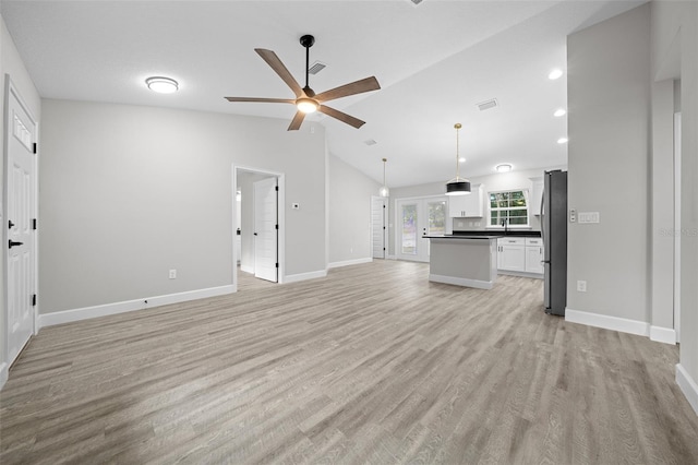 unfurnished living room featuring ceiling fan, light hardwood / wood-style floors, lofted ceiling, and french doors