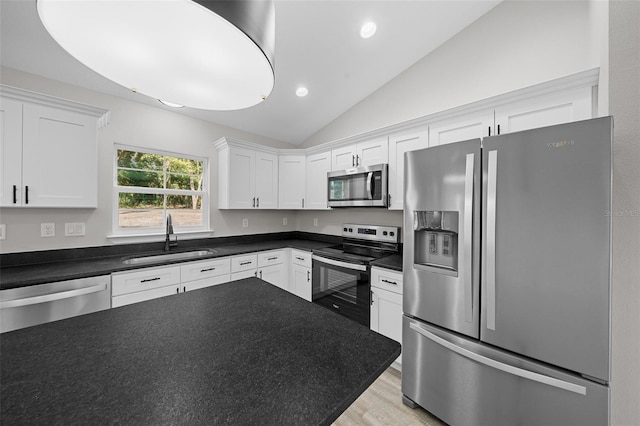 kitchen with white cabinetry, sink, stainless steel appliances, and lofted ceiling