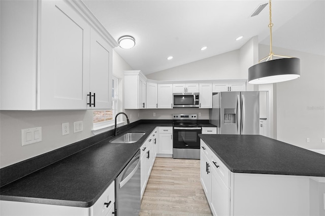 kitchen with stainless steel appliances, vaulted ceiling, sink, white cabinetry, and hanging light fixtures