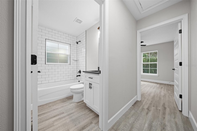 full bathroom featuring hardwood / wood-style floors, vanity, toilet, and tiled shower / bath