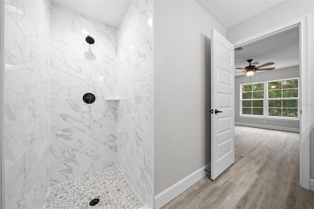 bathroom with ceiling fan, hardwood / wood-style floors, a textured ceiling, and tiled shower