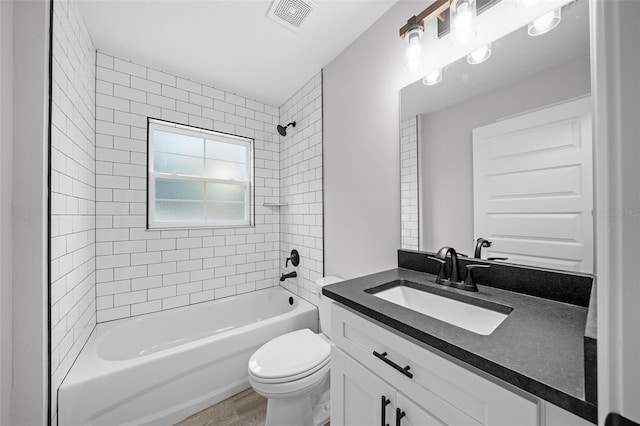 full bathroom featuring hardwood / wood-style flooring, tiled shower / bath combo, toilet, and vanity