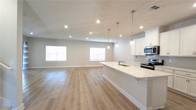 kitchen featuring hanging light fixtures, white cabinetry, stainless steel appliances, and a kitchen island with sink