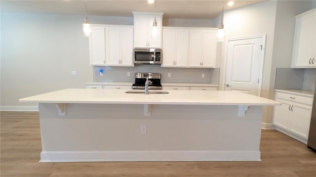 kitchen with backsplash, stainless steel appliances, and a kitchen island with sink