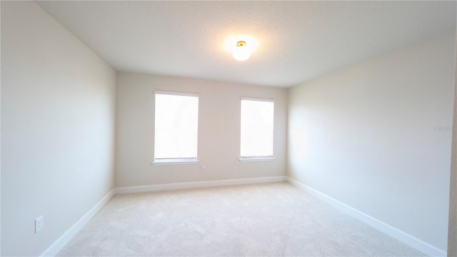 unfurnished room with a textured ceiling and light carpet