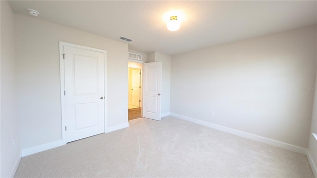 unfurnished bedroom with light carpet and a closet