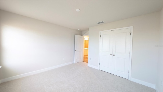 unfurnished bedroom with light colored carpet and a closet