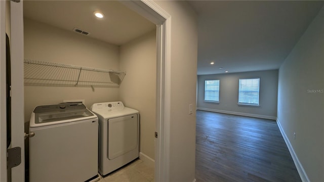 clothes washing area with washer and dryer and light wood-type flooring