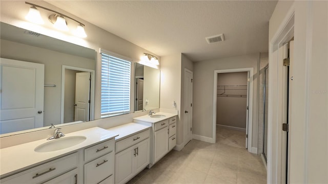 bathroom featuring tile patterned floors, vanity, an enclosed shower, and a textured ceiling