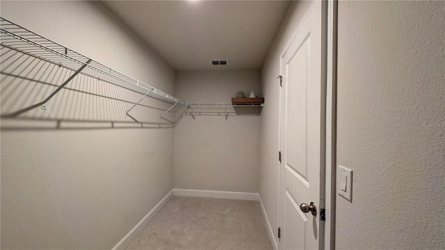 walk in closet featuring light colored carpet