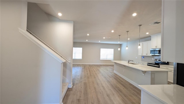 kitchen with stainless steel appliances, decorative light fixtures, a breakfast bar, sink, and white cabinetry