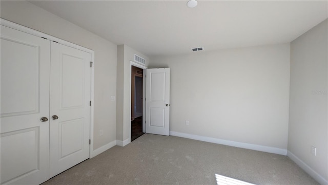 unfurnished bedroom with a closet and light colored carpet