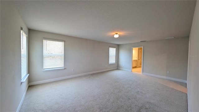 spare room featuring a textured ceiling and light carpet