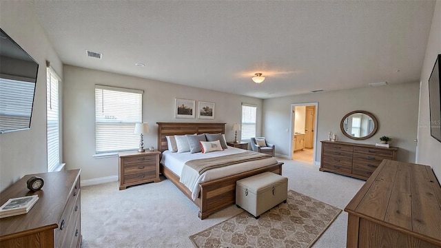 carpeted bedroom with a textured ceiling and ensuite bath