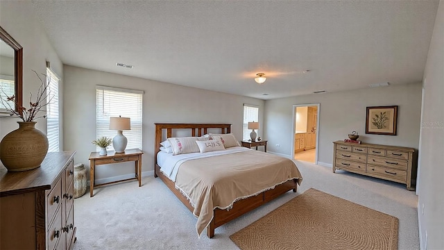 bedroom featuring multiple windows, a textured ceiling, connected bathroom, and light colored carpet