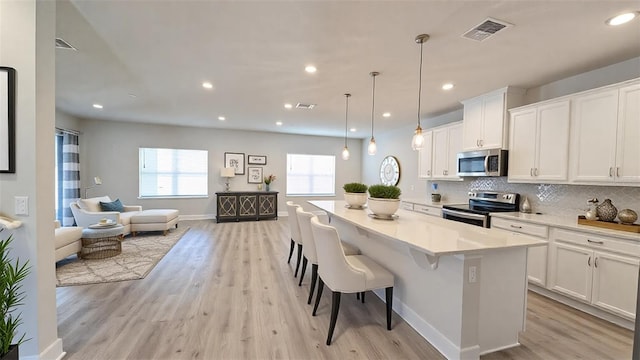 kitchen with white cabinetry, appliances with stainless steel finishes, a kitchen island, and a breakfast bar area