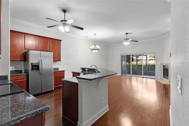 kitchen featuring a kitchen island with sink, ceiling fan with notable chandelier, crown molding, sink, and stainless steel fridge