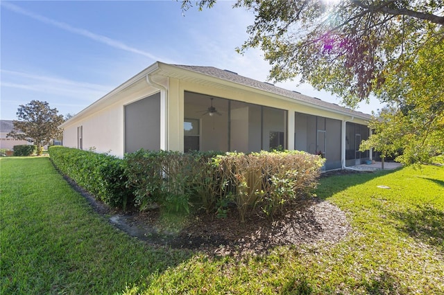 view of side of property featuring a sunroom, a yard, and ceiling fan