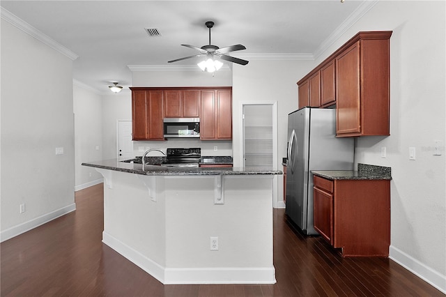 kitchen with dark stone countertops, an island with sink, and appliances with stainless steel finishes