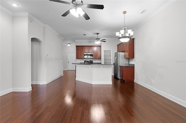 kitchen featuring a kitchen breakfast bar, a center island with sink, stainless steel refrigerator, and ornamental molding