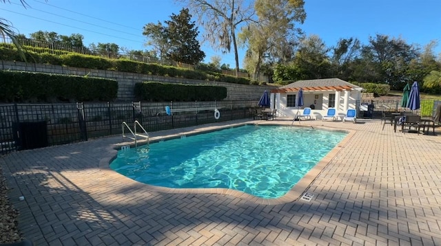 community pool with an outdoor structure, a storage structure, a patio area, and fence