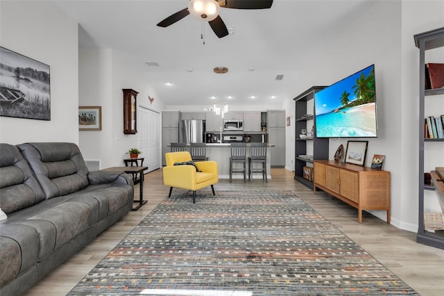 living room featuring built in features, light hardwood / wood-style flooring, ceiling fan, and lofted ceiling