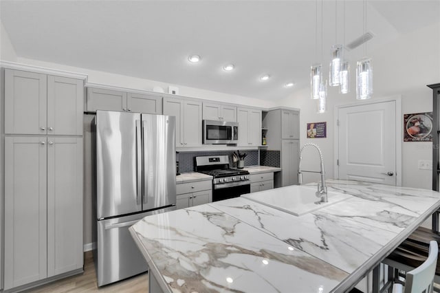 kitchen featuring light stone counters, a center island with sink, stainless steel appliances, and sink