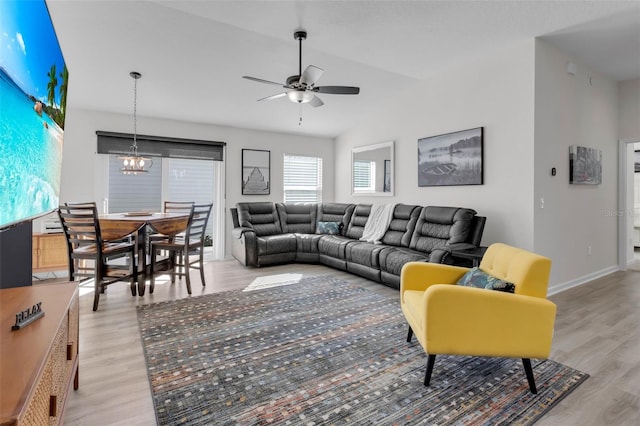 living room with ceiling fan with notable chandelier and light wood-type flooring