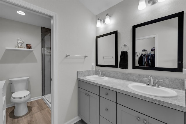 bathroom with hardwood / wood-style flooring, vanity, toilet, and a shower with door