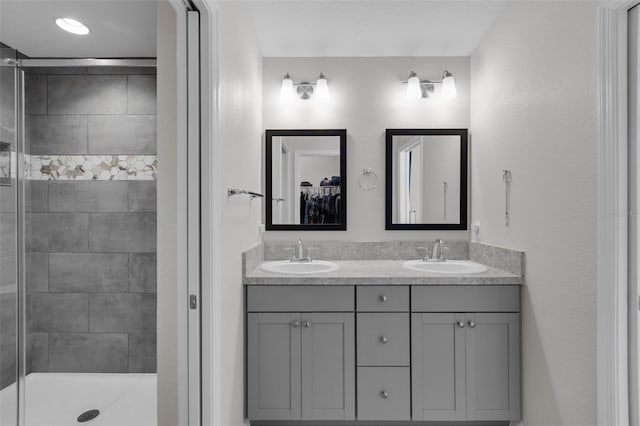 bathroom with tiled shower and vanity