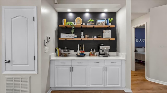 bar featuring light hardwood / wood-style flooring and white cabinetry