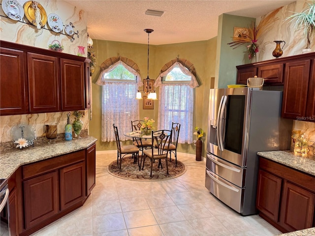 kitchen with light stone countertops, stainless steel refrigerator with ice dispenser, light tile patterned floors, an inviting chandelier, and hanging light fixtures