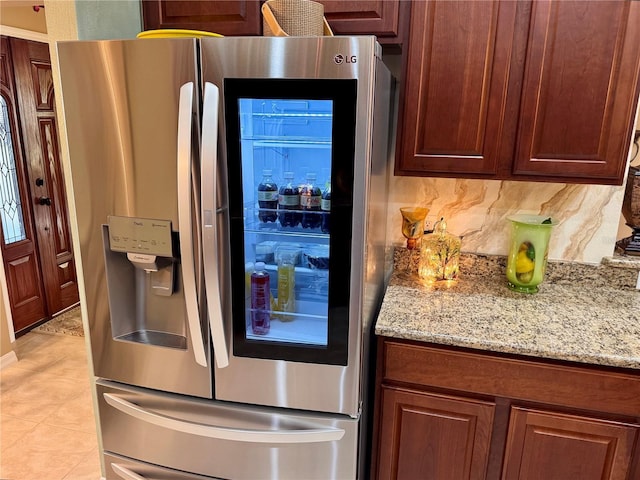 kitchen featuring decorative backsplash, stainless steel fridge with ice dispenser, light tile patterned floors, and light stone counters