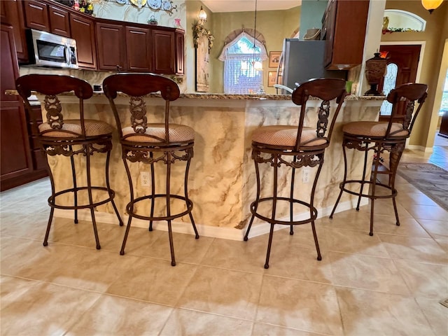 interior space featuring light stone counters, light tile patterned floors, decorative light fixtures, and appliances with stainless steel finishes