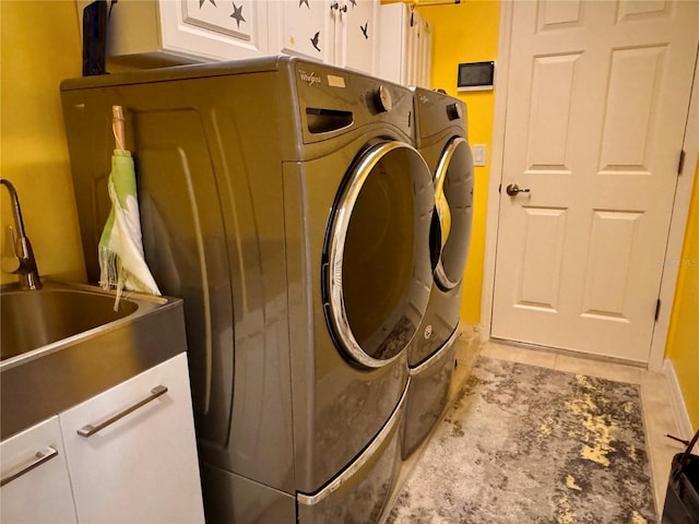 clothes washing area featuring washer and clothes dryer, cabinets, and sink