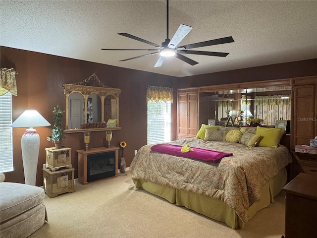 carpeted bedroom featuring ceiling fan and a textured ceiling