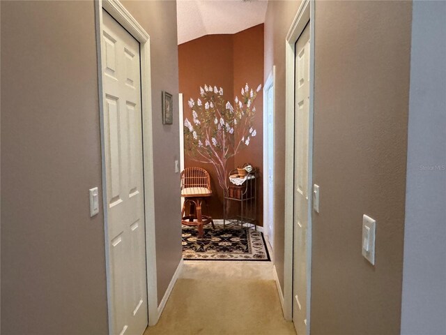 hall with carpet and vaulted ceiling