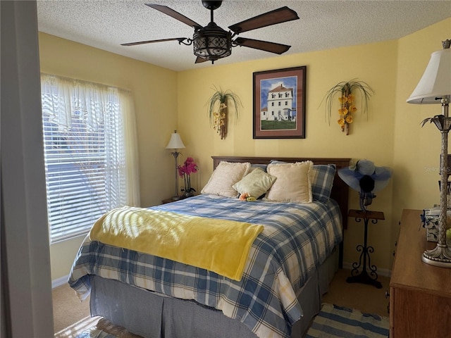 carpeted bedroom featuring ceiling fan and a textured ceiling