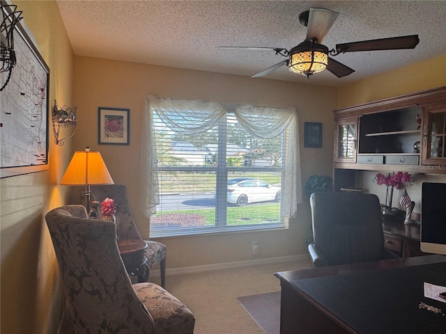 carpeted home office featuring ceiling fan and a textured ceiling