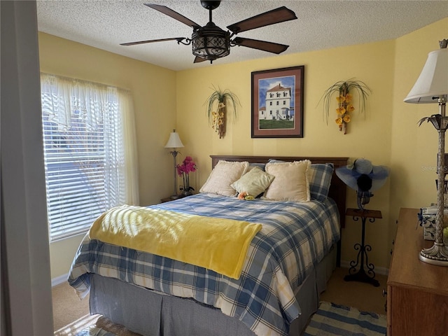 bedroom with carpet flooring, a textured ceiling, baseboards, and a ceiling fan
