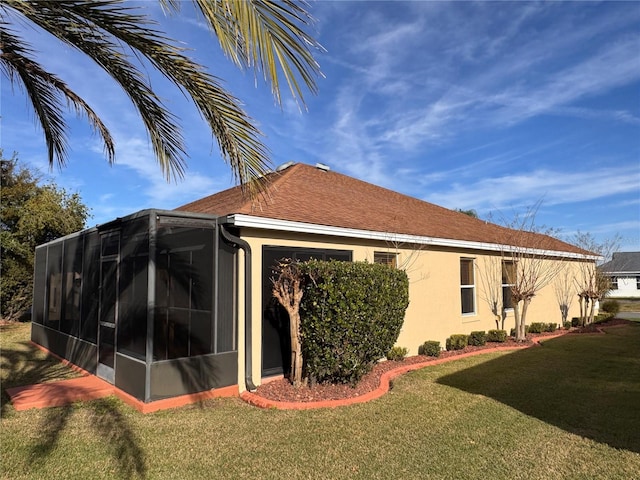 rear view of house featuring a lawn and stucco siding