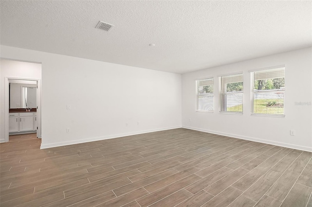 spare room featuring hardwood / wood-style floors and a textured ceiling