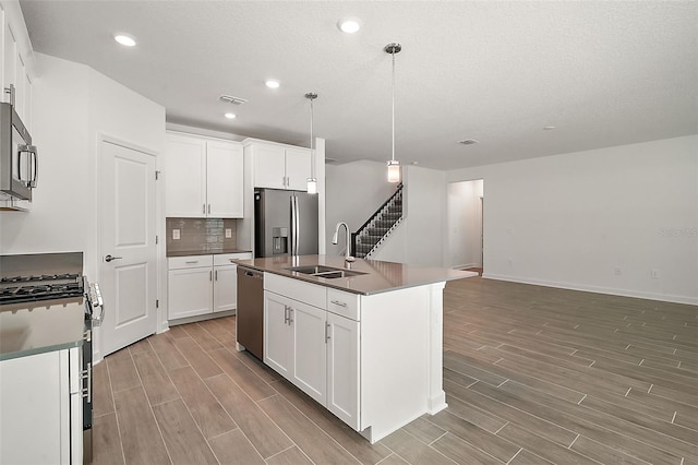 kitchen with stainless steel appliances, sink, a center island with sink, and white cabinets